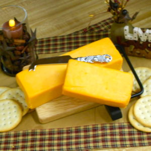 1 Year Nippy Aged Cheddar, two cheese blocks on a cutting board on a table 