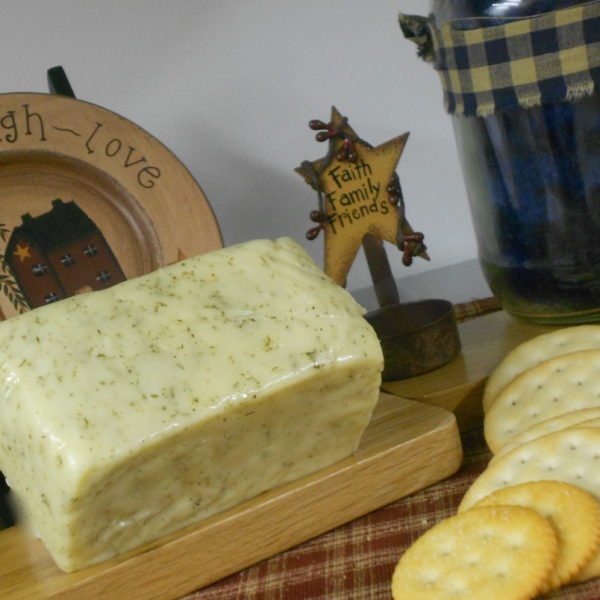 Dill Havarti cheese block on a cutting board on a table