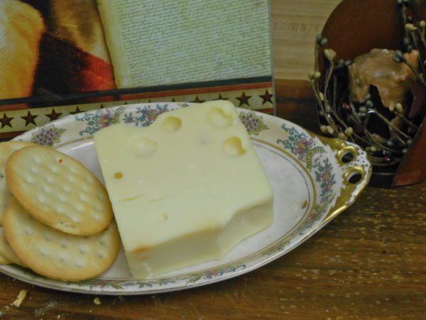 Hickory Smoked Extra Sharp Aged Swiss cheese block on a plate on a table